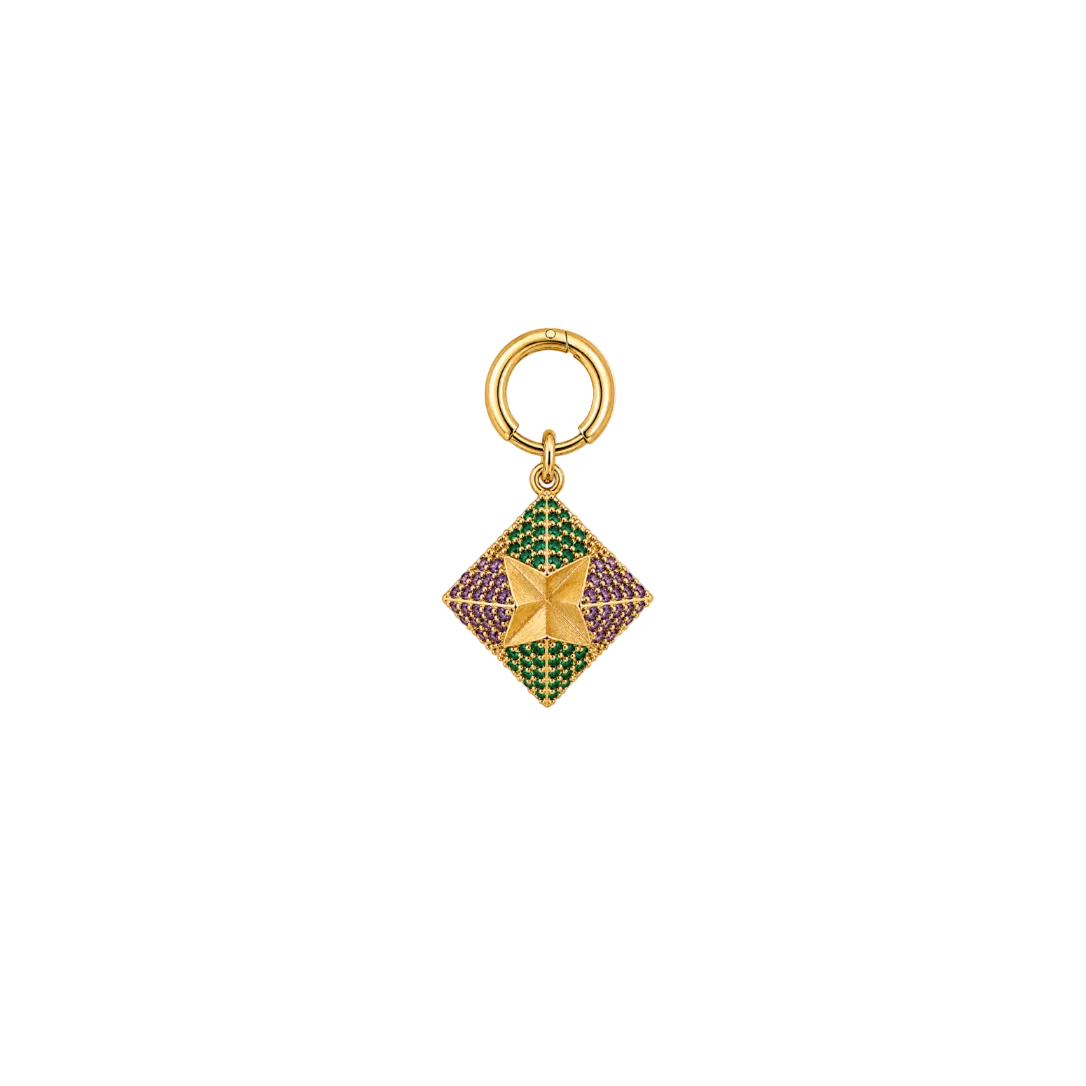 A gold-toned diamond-shaped charm with a central four-pointed star, decorated with green and purple pavé stones, hanging from a gold ring on a plain white background.