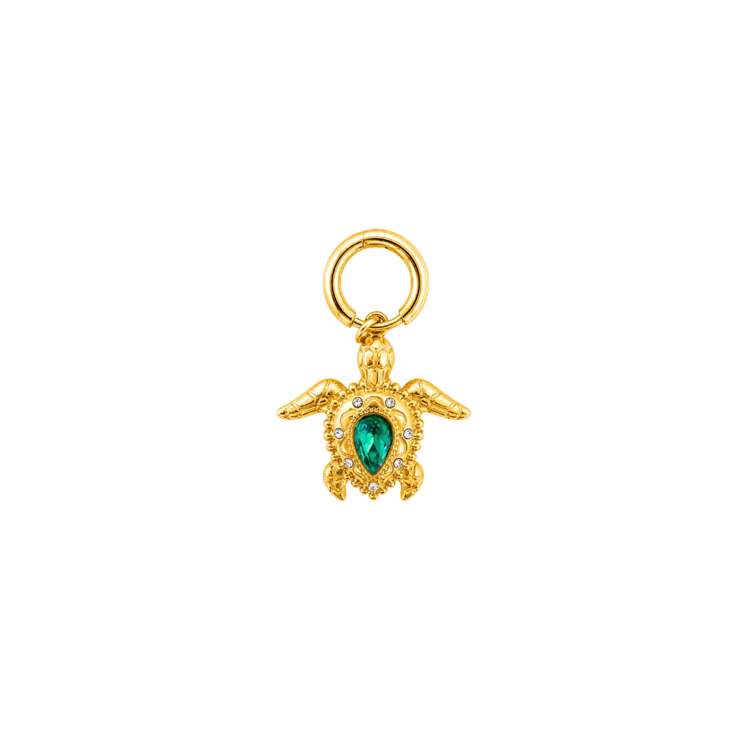 A gold turtle charm pendant featuring a green teardrop-shaped gemstone in the center, surrounded by small clear stones, with a gold ring at the top, shown on a plain white background.